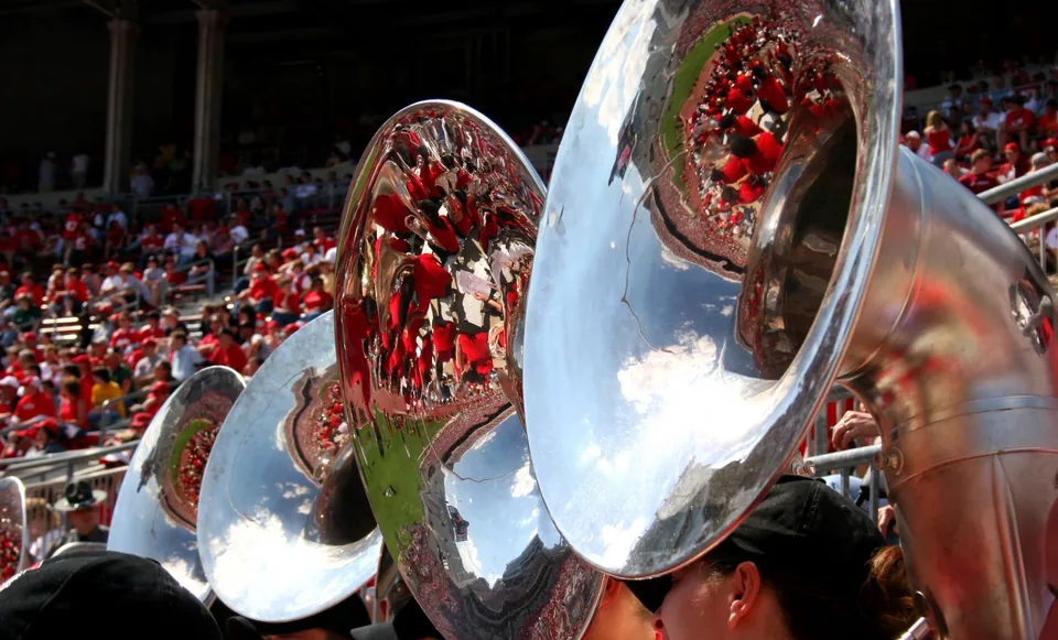 Sousaphones of the marching band reflecting the scarlet crowd